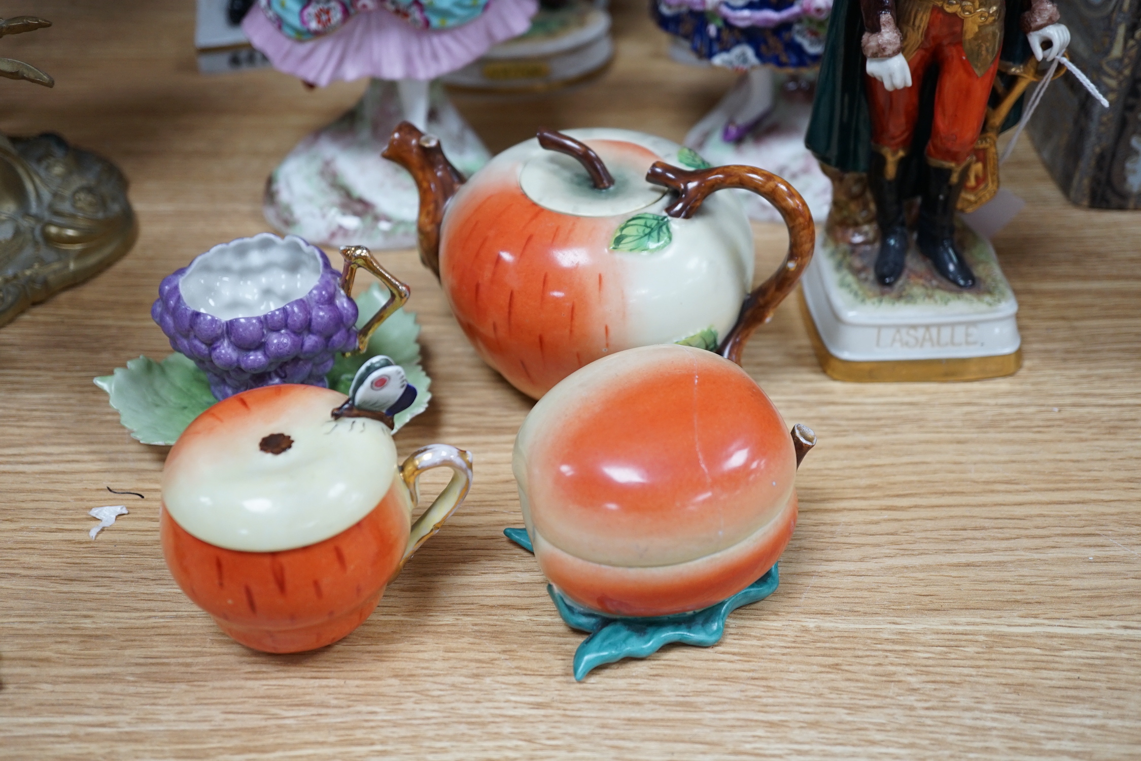 A group of Continental porcelain military figures, two porcelain figures of dancing females and four pieces of tableware in the form of fruit
